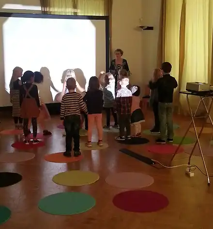 Eine Gruppe von Kindern vor einer großen Leinwand.