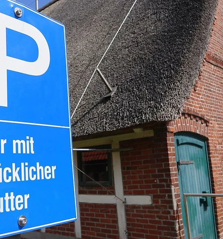 Blaues Parkplatzschild mit dem Hinweis: NUR MIT GLÜCKLICHER MUTTER