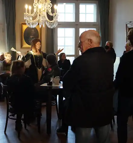 Eine Gästeführerin in historischem Gewand begrüßt eine Gruppe auf Schloss Agathenburg