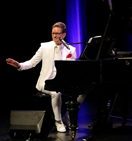 Foto Christian Mädler im weißen Anzug am Piano
