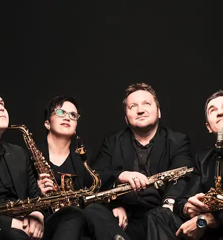 4saxess - Baroque goes Contemporary Das Quartett in schwarzer Konzertkleidung vor schwarzem Hintergrund mit ihren Saxophonen.