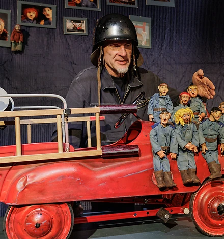 Puppenspieler Martin Karl mit Puppen und Feuerwehrauto in Miniatur.