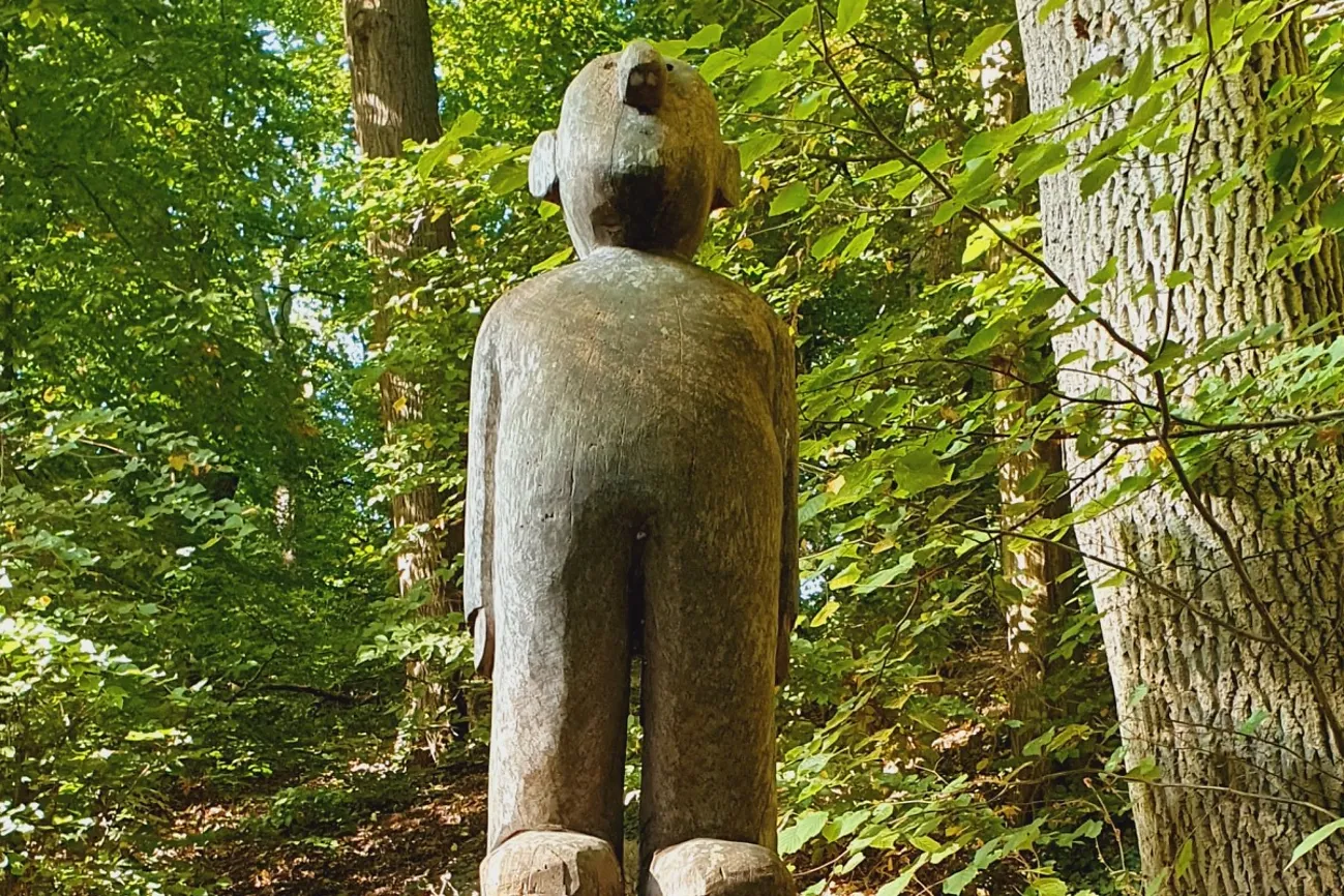 Eine aus Holz geschnitzte Figur eines Männchens steht mitten im Park.
