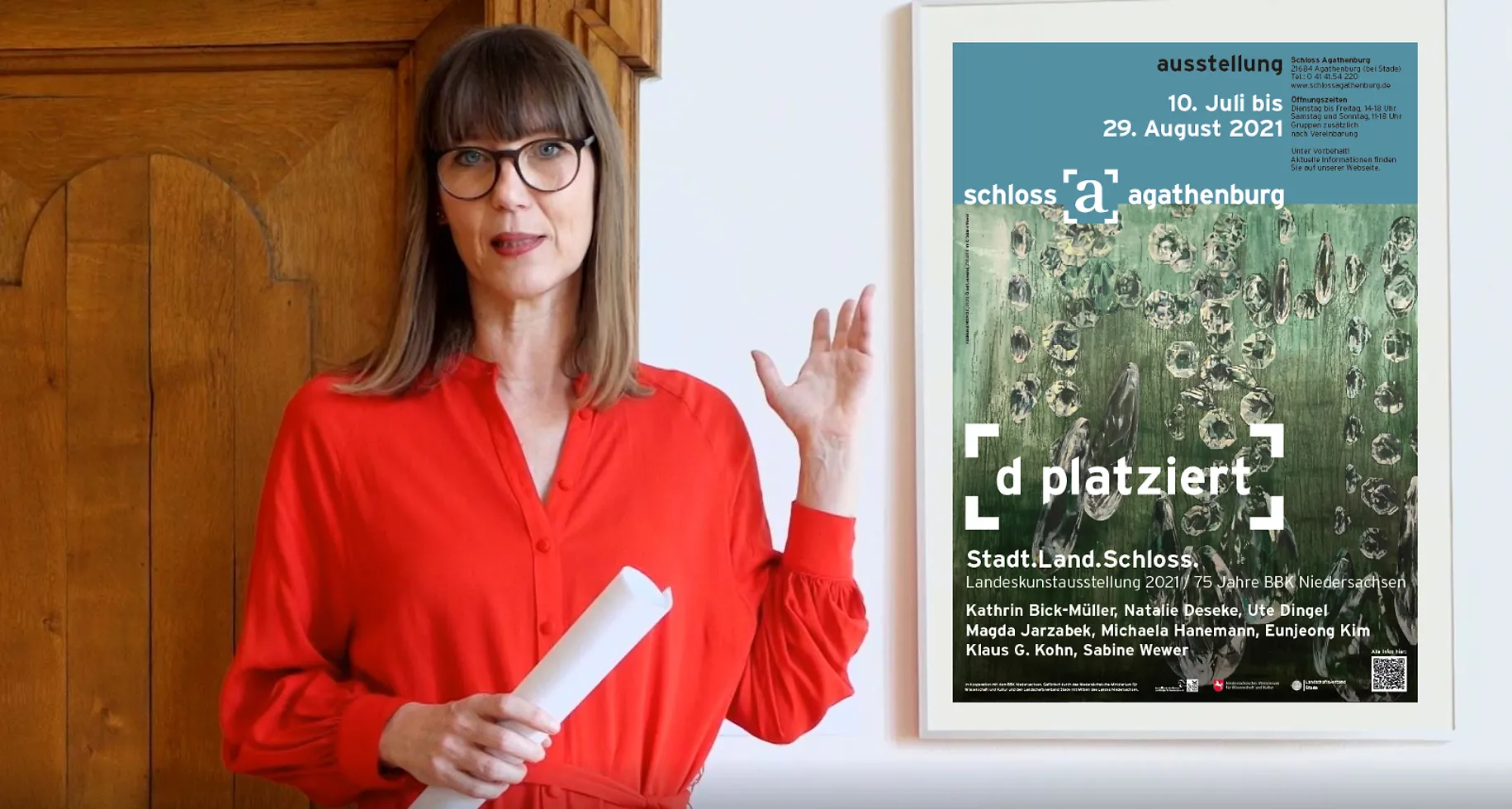 Claudia Rastzar zeigt auf das Plakat zur Ausstellung.