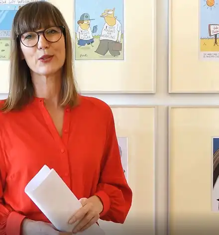 Claudia Rasztar führt durch die Karikaturenausstellung.