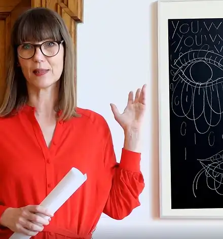 Claudia Rasztar zeigt auf ein Bild