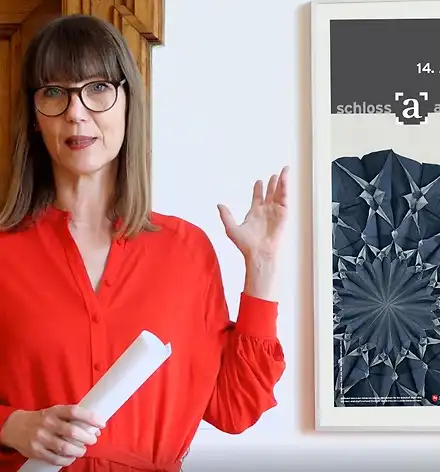 Kuratorinnenführung im August Claudia Rasztar zeigt auf das Plakat zur Ausstellung