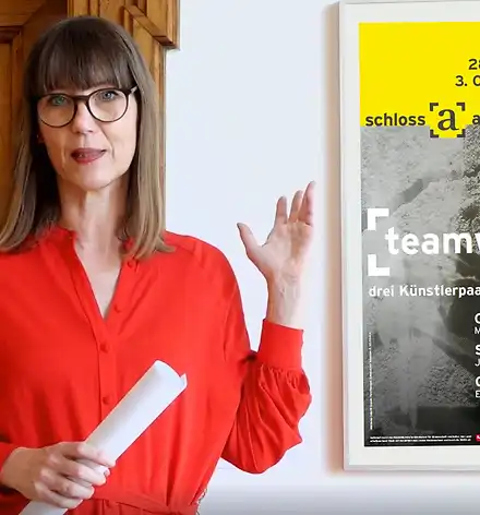 Kuratorinnenführung im Oktober Claudia Rasztar zeigt auf das Plakat zur Ausstellung.