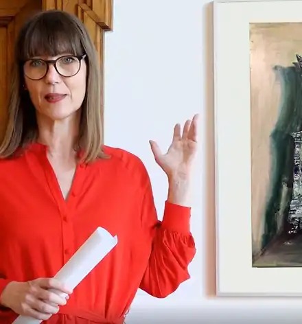 Claudia Rasztar zeigt auf ein gerahmtes Bild