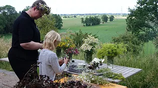 Eine Frau und ein Mädchen binden Blumenkränze