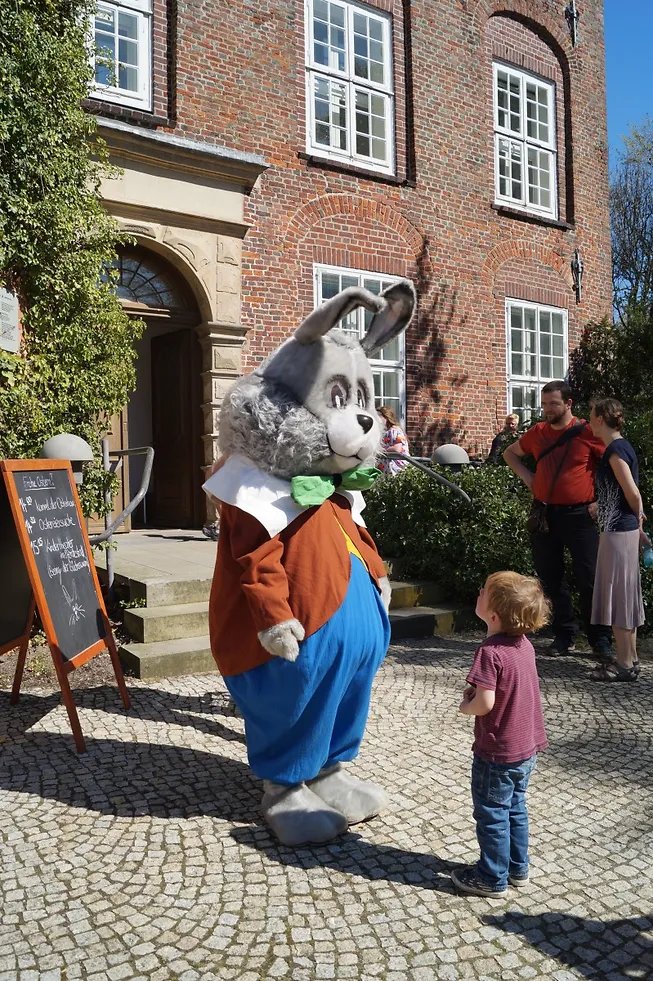 Osterhase und kleiner Junge vor Schloss Agathenburg