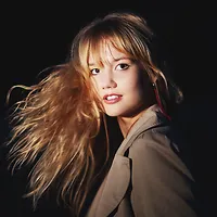 Fabia Mantwill Quintet - Sasa Ndio Sasa Ein Porträt von Fabia Mantwill. Die junge Frau ist vor einem schwarzen Hintergrund fotografiert und schwingt ihr langes blondes Haar.