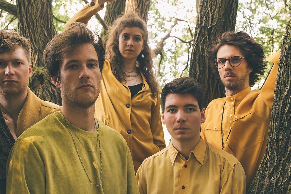 Gruppenbild des Quintetts, alle in Gelb gekleidet und zwischen Baumstämmen stehend.