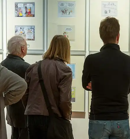 Führung durch die Karikaturenausstellung Eine Gruppe Besucherinnen und Besucher betrachtet gerahmte Karikaturen im Schloss.