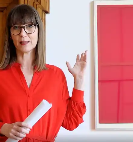 Kuratorinnenführung Claudia Rasztar zeigt auf ein Bild in der Ausstellung.