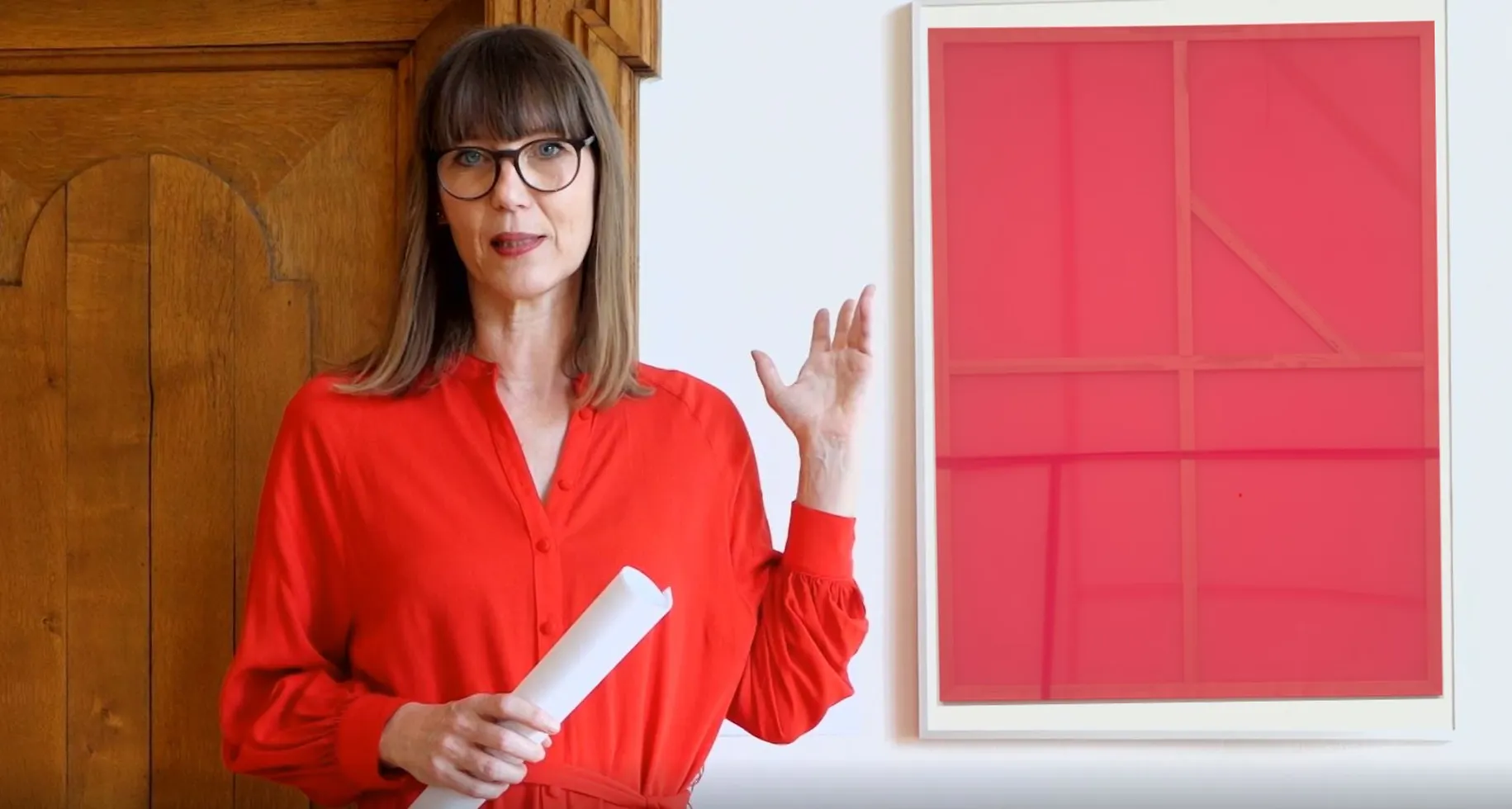 Claudia Rasztar zeigt auf ein Bild in der Ausstellung.
