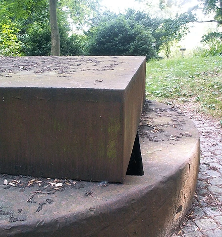 Foto der Skulptur, im Hintergrund sieht man das Grün des Parks.