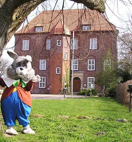 Vor dem Schloss winkt ein lebensgroßer Osterhase.