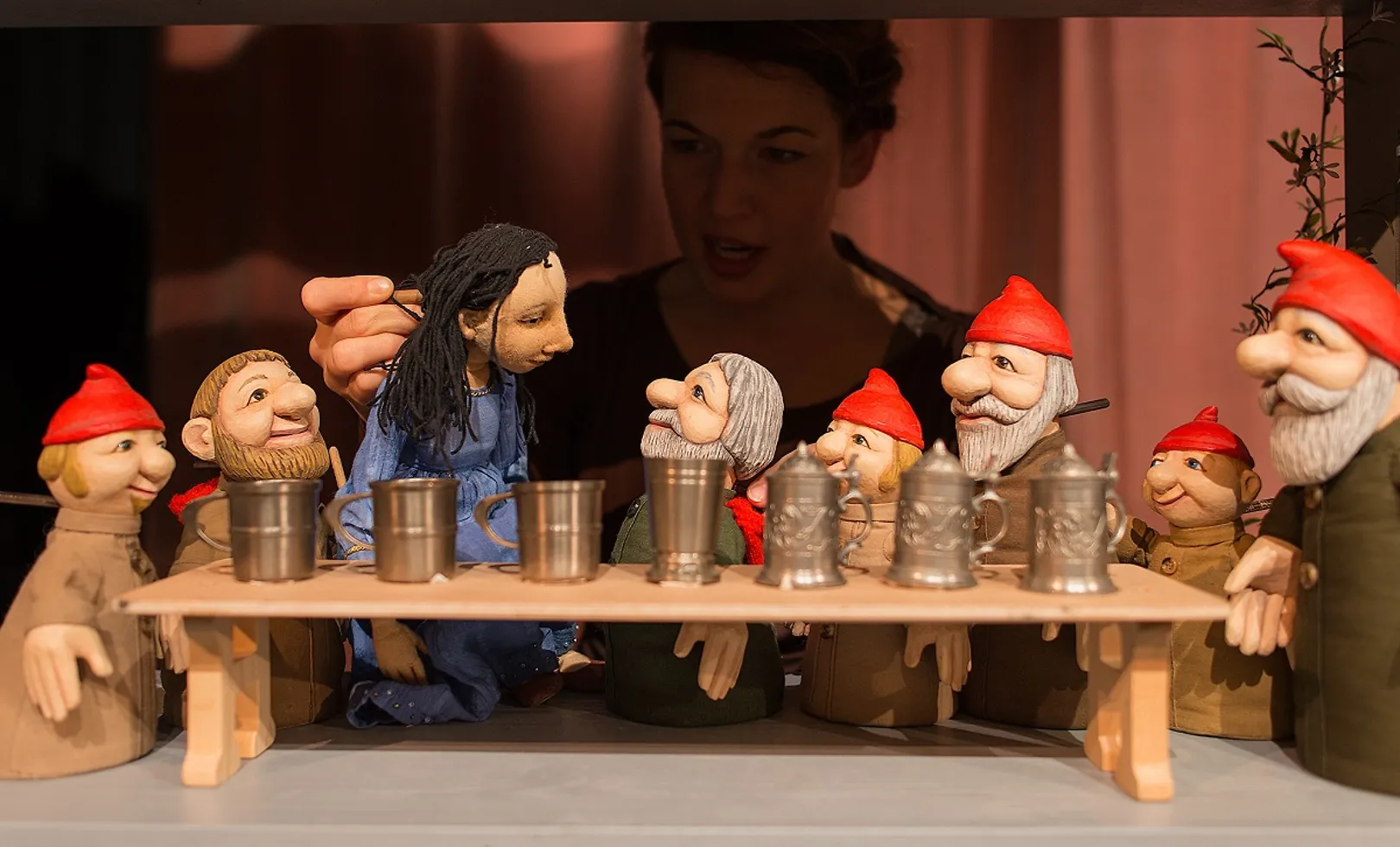 Im Vordergrund Handpuppen: Schneewittchen und die sieben Zwerge, die Spielerin im Hintergrund.