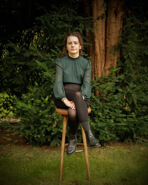 Danica Hobden sitzt auf einem Schemel im Grünen. 